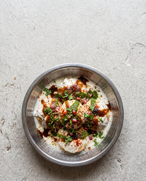 Indian dahi vada lentil dumplings in yogurt with chutneys and spices for Holi top view with copy space, vertical
