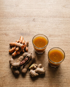 Indonesian jamu kunyit asam turmeric drink with fresh turmeric, ginger and tamarind top view with copy space, vertical