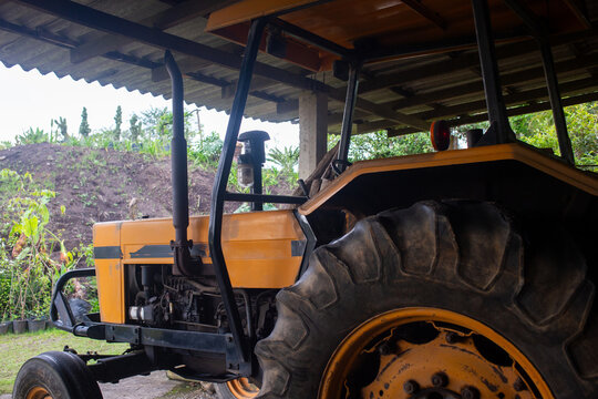 Agricultural tractor parked in open shed in a cloudy day