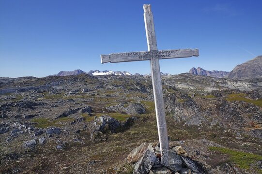 A cross on a rocky hill against a beautiful mountain backdrop, Tiniteqilaaq, Tasilaq, Arctic, Greenland, Denmark