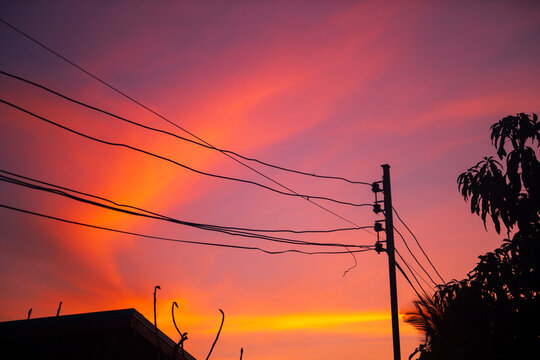 Silhouette of a wooden utility pole with power lines against a vibrant purple twilight sky.
A stunning, atmospheric photograph capturing a rustic wooden utility pole and an intricate web