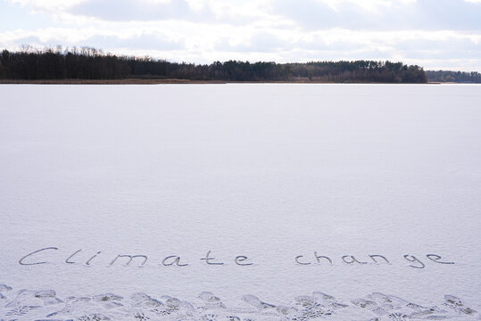 Written CLIMATE CHANGE on snow background message ice outdoor on ground in winter. Writing text sign drawing on field in frozen background. Weather changing cold season has arrived environment