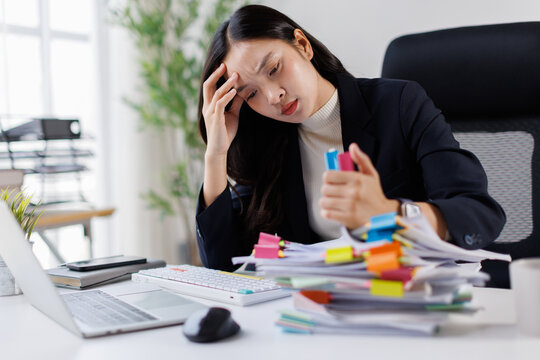Businesswoman experiencing severe headache and burnout from excessive workload, feeling overwhelmed by a mountain of paperwork and office responsibilities, struggling with stress