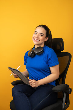 Young latina woman working with a digital tablet and headphones on a yellow background