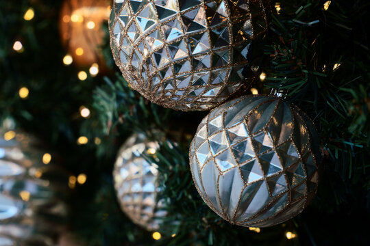 Silver Christmas Ornaments Hanging Among Warm Tree Lights