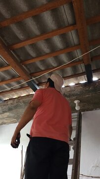 Inspecting Wooden Roof Beam After Applying Protective Paint Sealant