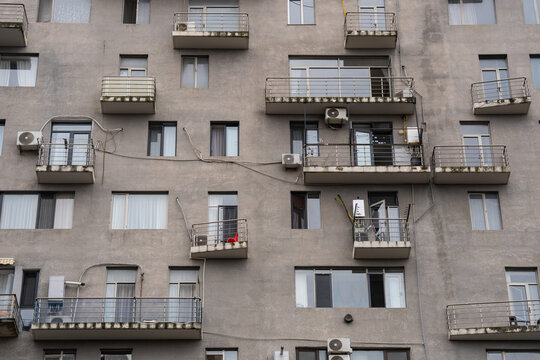 Weathered apartment building with messy air conditioners jutting out from walls in Batumi, Georgia, wiring hanging across residential house structure wall with haphazard balconies damaged by mold.