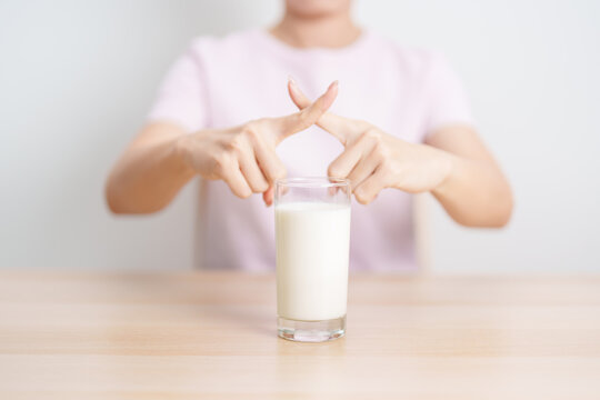 Lactose intolerance and Milk allergy. woman hand stop and refuse Milk, having abdominal cramps and pain when drink Cow Milk. Symptom stomach ache, Dairy intolerant, Nausea, Bloating, Gas and Diarrhea