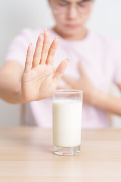 Lactose intolerance and Milk allergy. woman hand stop and refuse Milk, having abdominal cramps and pain when drink Cow Milk. Symptom stomach ache, Dairy intolerant, Nausea, Bloating, Gas and Diarrhea