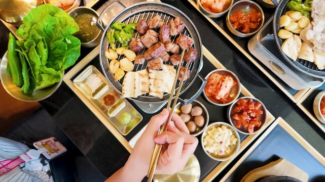 Top View of Person Eating Korean Barbecue with Banchan Side Dishes