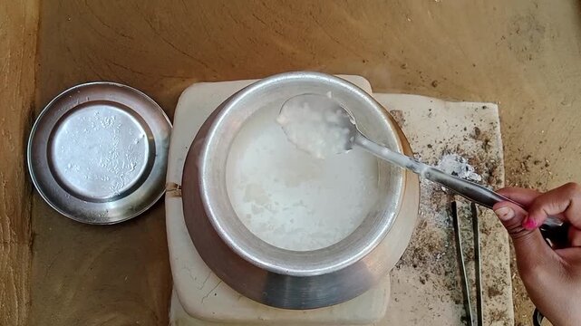 indian village woman stirring sweet sago pudding on a clay stove