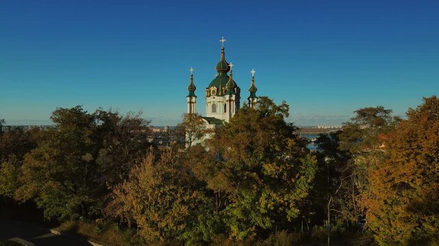 Green domes of Saint Andrews Church framed by colorful autumn trees