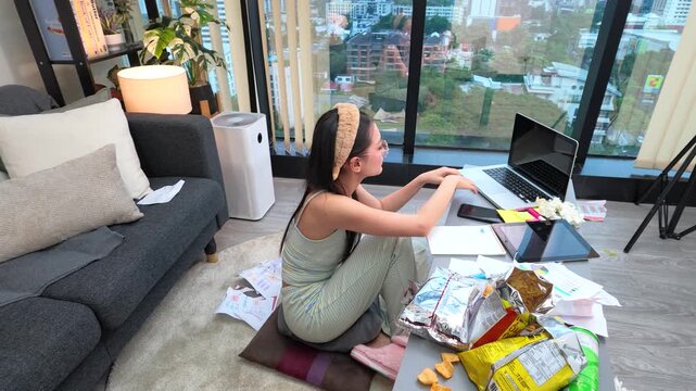 Young Asian Woman in Pajamas Working on Laptop from Living Room Floor