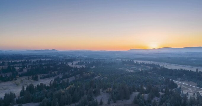 Aerial time-lapse of sunrise over rare spruce forest and sandy grassland in autumn, morning mist on horizon, Inner Mongolia, China
