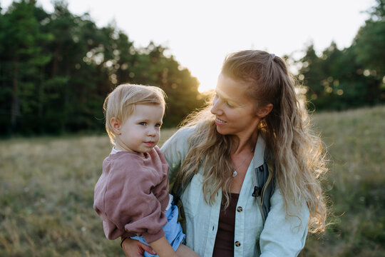 Mother holding young child during family outing in nature.