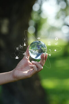 Hand Holding Crystal Glass Globe with Environmental and ESG Icons