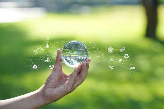 Hand Holding Crystal Glass Globe with Environmental and ESG Icons