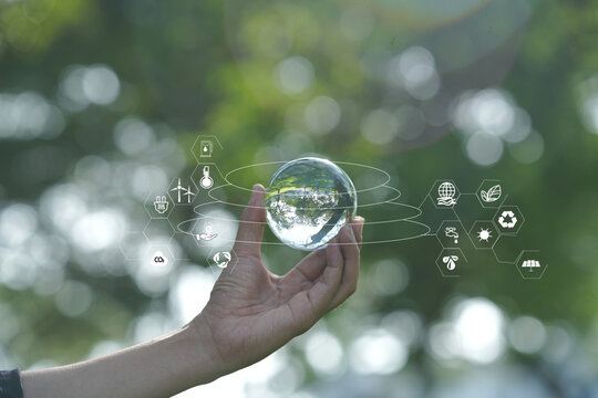 Hand Holding Crystal Glass Globe with Environmental and ESG Icons