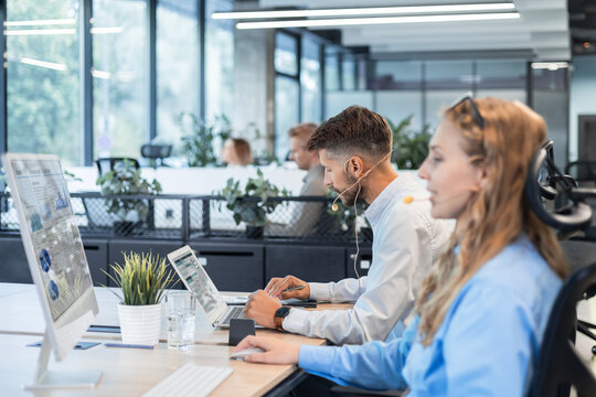 Portrait of call center worker accompanied by her team. Smiling customer support operator at work.