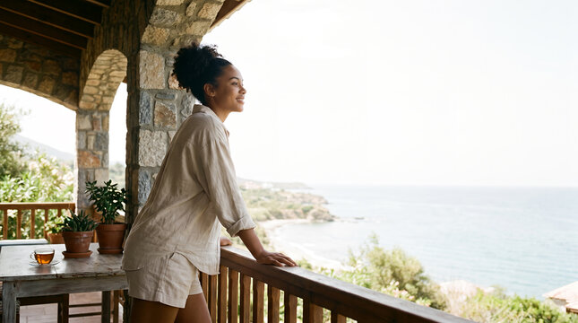 Woman relaxing with tea on coastal terrace overlooking ocean