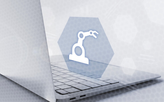 Una moderna computadora port&aacute;til con una interfaz futurista que muestra un icono de brazo rob&oacute;tico en una pantalla hexagonal, simbolizando la automatizaci&oacute;n industrial y la manufactura digital.