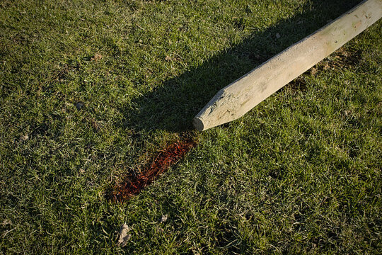 Fence post laying in a field with hole placement marked on the grass for fencing purposes