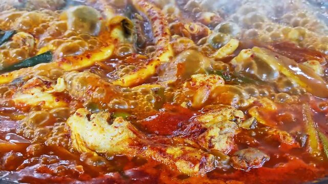가마솥 뚜껑에서 매콤한 한국식 닭볶음탕이 보글보글 끓고 있는 클로즈업.(Close up of spicy korean braised chicken stew boiling in a large cauldron.)