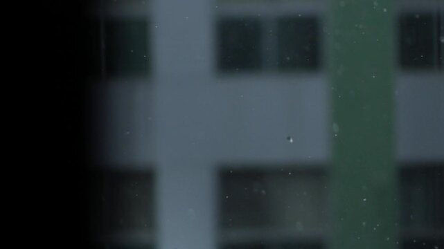 Rainy Window View of Distant Buildings Through Falling Raindrops, Moody Urban Blur