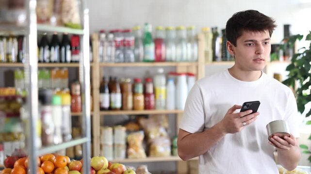 Guy in store scans barcode QR code on tin cans of preserves. With help of mobile app, buyer receives information about product. He checks manufacturers data in registry database of national agency 