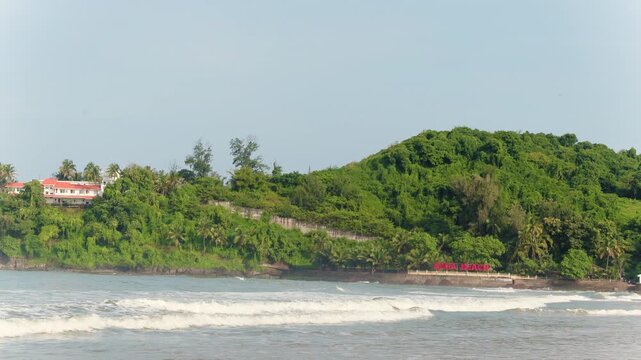 Dona Paula beach sign in Goa India with lush green hill and ocean