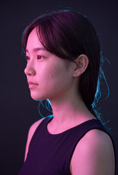 Profile portrait of a young woman in colored studio lighting for editorial background and fashion banner design