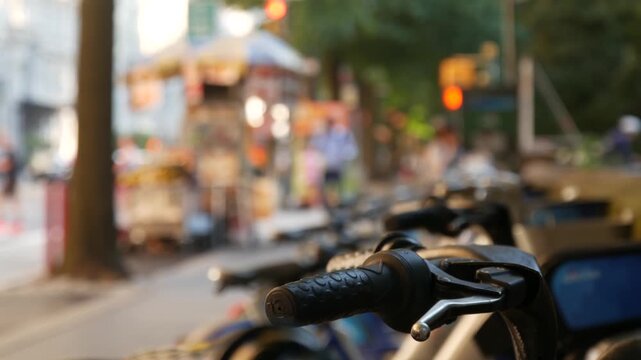 Manhattan Midtown street New York City, United States. Rental bicycle parking, Central Park West summer trees greenery. Bike for rent in row. People pedestrian on sidewalk pavement. Hot dog fast food.