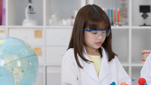 Young Girl in Lab Coat and Goggles Studying Science in Classroom