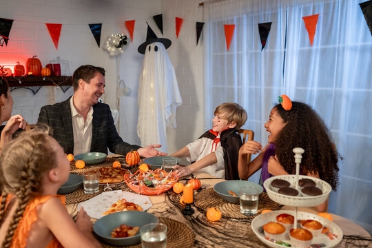 Multiracial family celebrating Halloween party together in house. 