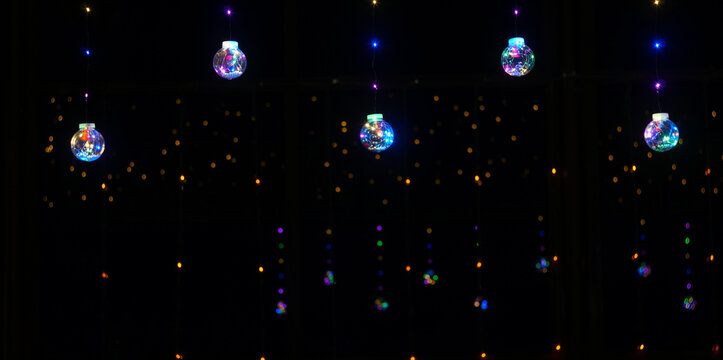 Hanging Christmas LED glass balls on a black background.