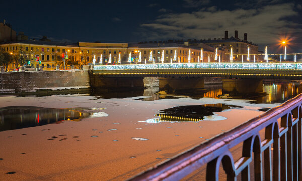 Saint Petersburg. Night cityscape with Semyonovsky Bridge 1857 across frozen Fontanka River in festive Christmas lighting. New Year and Christmas holidays in Northern Capital