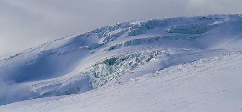 Snow covered glacier with deep blue ice crevasses