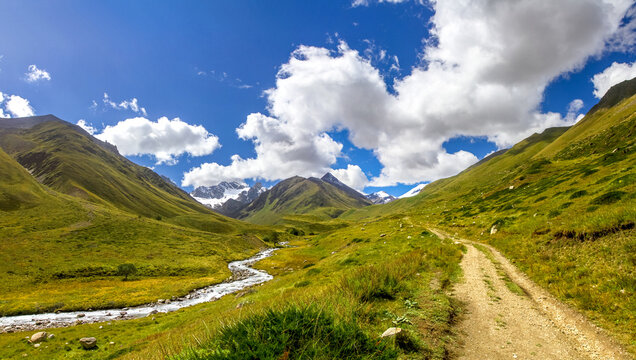 Dirt path winding through a beautiful green mountain valley
