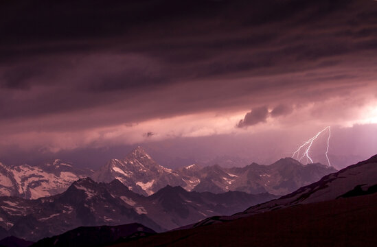 Dramatic lightning storm illuminates snowy mountain peaks