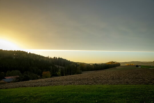 Golden evening light illuminates the autumn landscape of the Bavarian Forest in Bavaria, Germany, creating a warm sky above wooded hills and forested slopes.