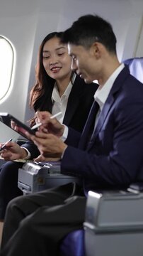 Business colleagues collaborating on tablet during airplane travel.
