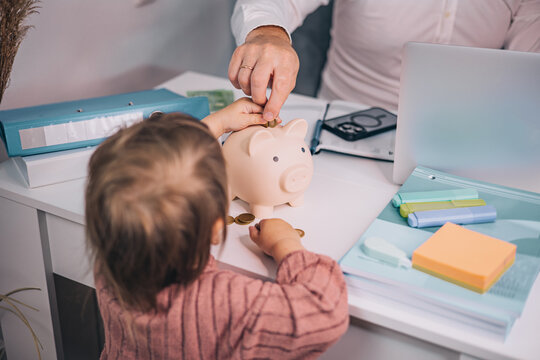 Top view of family counting coins and saving money in piggy bank at desk, home budget overview, financial planning together, future property fund