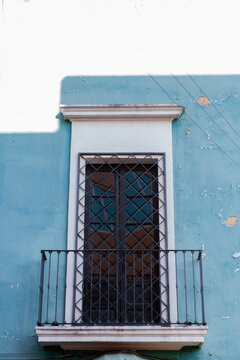 Weathered Blue Building Facade with a Barred Window