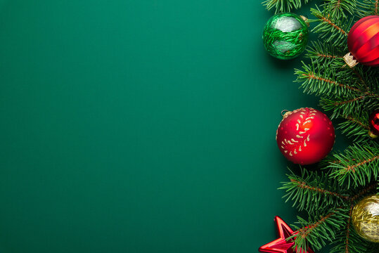 Christmas background with fir tree branches and golden and red ornaments on green, flat lay holiday border composition with copy space. Happy New Year greeting card.