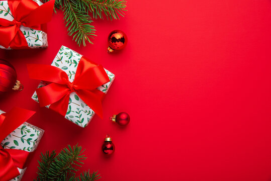 Red Christmas and Happy New Year holiday background with gift boxes, red ribbon bows and festive ornaments, flat lay with copy space. Greeting card.