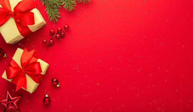 Red Christmas and Happy New Year holiday background with gift boxes, red ribbon bows and festive ornaments, flat lay with copy space. Greeting card.