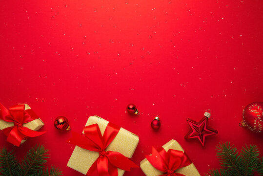 Red Christmas and Happy New Year holiday background with gift boxes, red ribbon bows and festive ornaments, flat lay with copy space. Greeting card.