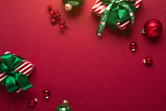 Red Christmas and Happy New Year holiday background with gift boxes, green ribbon bows and festive ornaments, flat lay with copy space. Greeting card.