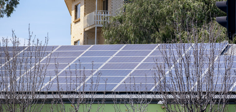 A large array of solar photovoltaic panels covering the flat rooftop of a commercial or institutional building in Australia. Renewable energy technology in Australian urban buildings.