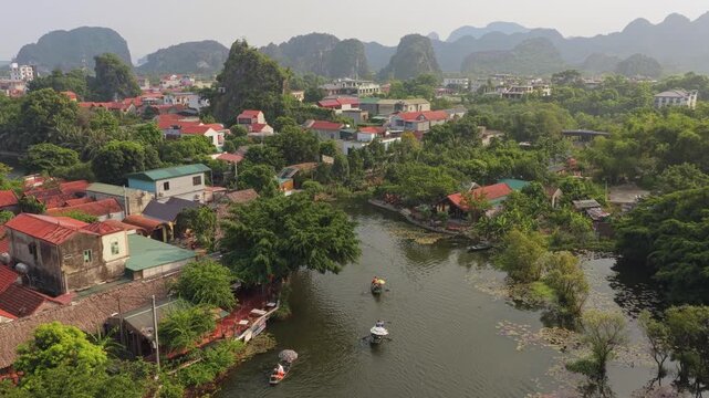 Majestic aerial scenery of tam coc village in vietnam, with traditional sampan boats rowing on the ngo dong river and lush jungle mountains